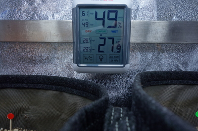 Ein digitales Hygrometer zeigt eine Luftfeuchtigkeit von 49% und eine Temperatur von 27,9°C an, daneben sind die Ränder von zwei Stofftöpfen zu sehen.