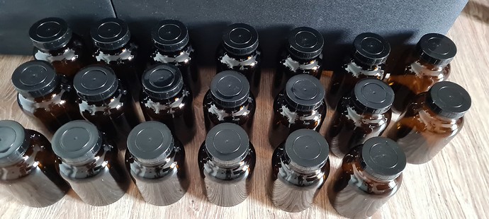 Viele braune Glasflaschen mit schwarzen Schraubverschlüssen, die auf einer Holzoberfläche stehen.