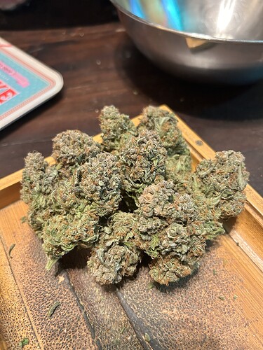 Nahaufnahme von getrimmten Cannabis-Blüten auf einem hölzernen Tablett.