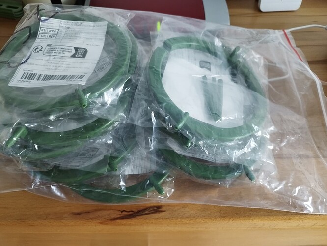 Mehrere grüne Ringbewässerungseinheiten in Plastik verpackt, die auf einem Holztisch liegen.