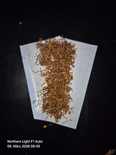 Ein auf einem weißen Papier ausgebreitetes, fein zerkleinertes Cannabis-Produkt, das für den Konsum vorbereitet wurde.