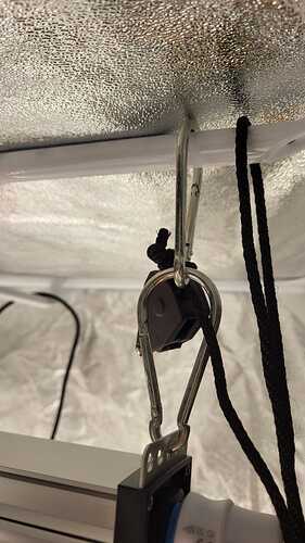 Nahaufnahme einer Lampenaufhängung mit Karabiner und Seilzugratsche in einem Growzelt.