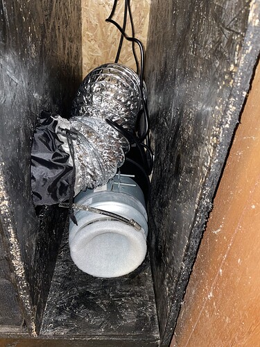 Ein Lüftungsrohr mit einem Filter und einem Lüfter, der in einem dunklen, engen Raum installiert ist.