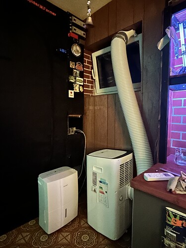 Ein Grow-Setup mit einem Growzelt, einem Luftentfeuchter und einem mobilen Klimagerät mit Abluftschlauch aus dem Fenster.