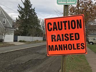 caution-raised-manholes-road-construction-sign-bright-orange-sign-warning-drivers-raised-manholes-photo-was-taken-203850436